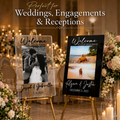 Two personalized acrylic wedding welcome signs on gold easels in a decorated reception venue. The left sign has a clear background with a black-and-white couple photo and the names Joseph & Gabriella with the date 5.